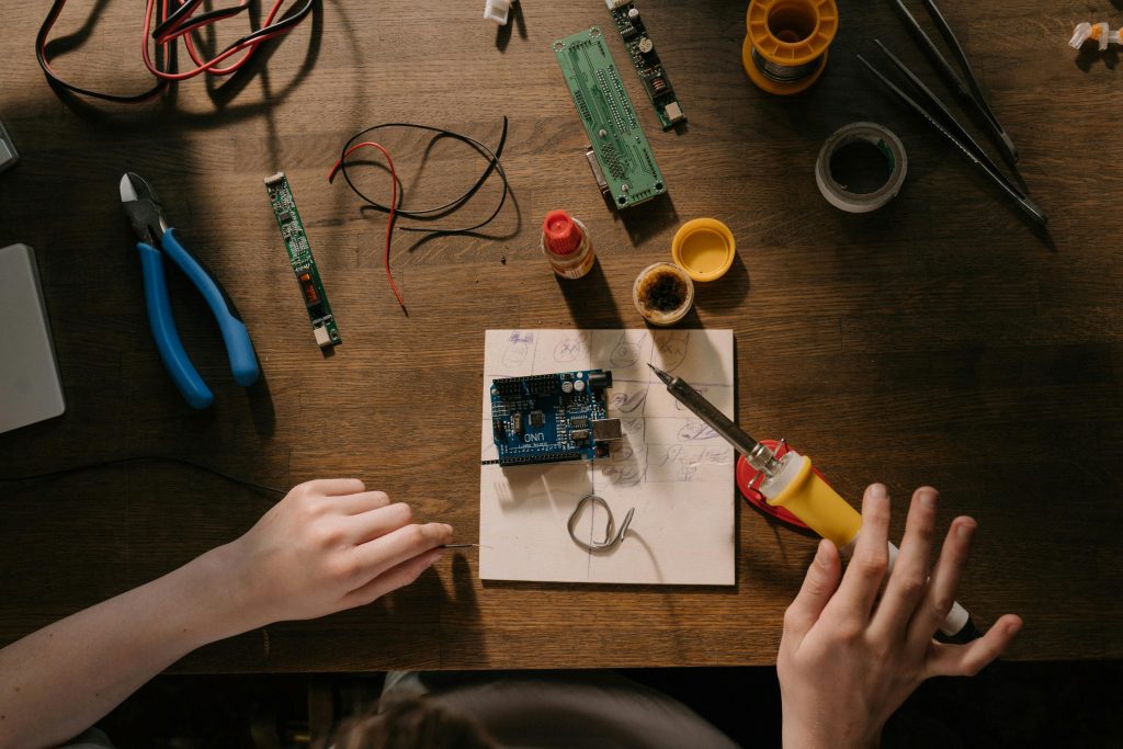 Hands soldering an Arduino Uno prototype on a workbench